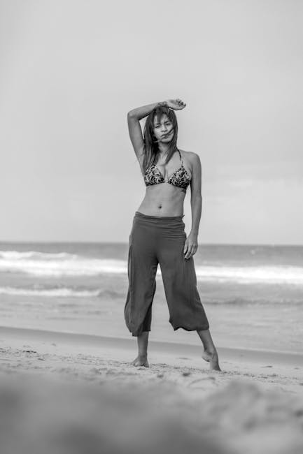 Woman in a peaceful yoga pose outdoors by the water with sunset background